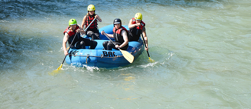  Eine Gruppe von Menschen auf einem Schlauchboot macht eine Raftingtour auf einem Fluss.