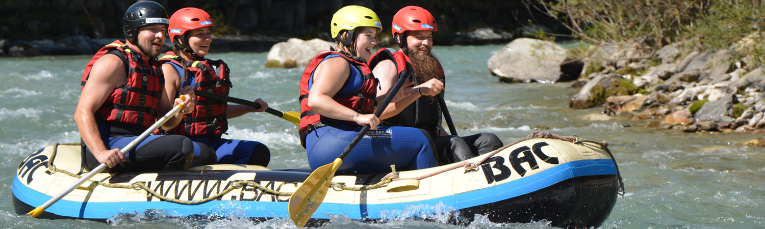 Eine Familie unternimmt mit einem Schlauchboot eine Rafting Tour auf einem Fluss.