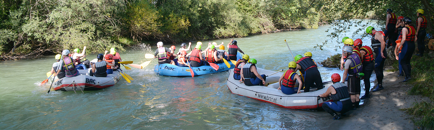 Drei Teams unternehmen mit einem Schlauchboot eine Rafting Tour auf einem Fluss.