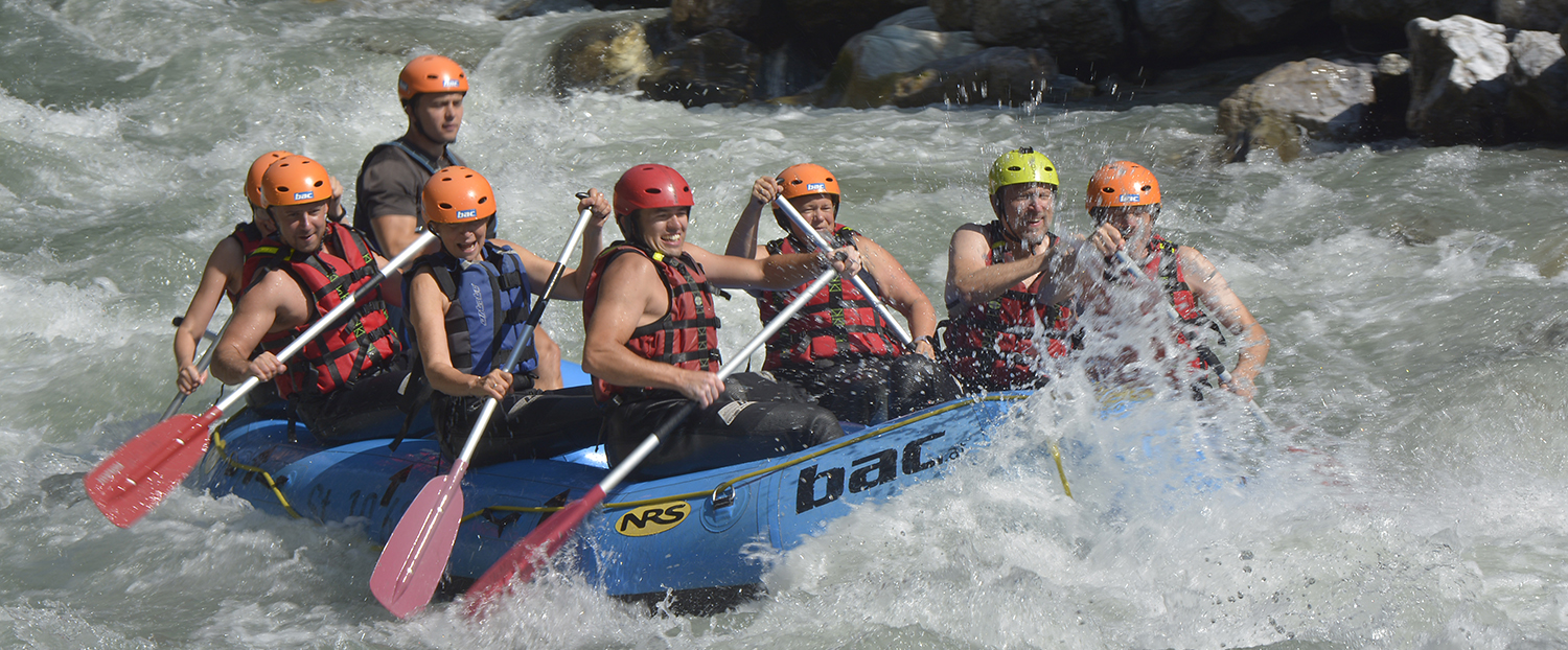 Mit einem Schlauchboot macht eine Menschengruppe eine Rafting Tour auf dem Fluss.